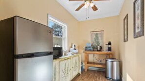 A compact kitchen with a stainless steel refrigerator, a microwave, a toaster, and a small wooden table with a hanging plant. - Shenandoah Valley Cottage (Stanley)
