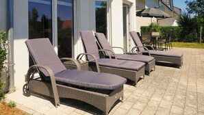A patio with four wicker lounge chairs with cushions, a table, and an umbrella. - New! Modern vacation home for 6 in Heringsdorf, Haus Sand (Heringsdorf)