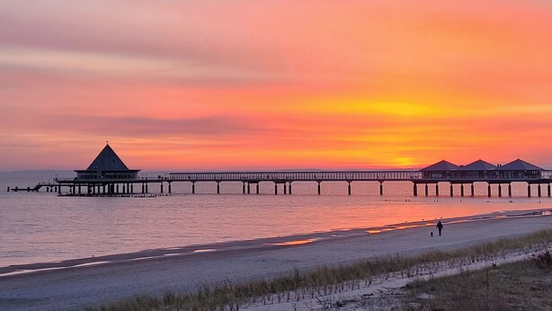 A pier extending into calm waters during sunset, with a building and several covered structures at the end. - New! Modern vacation home for 6 in Heringsdorf, Haus Sand (Heringsdorf)