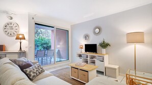 Ein modernes Wohnzimmer mit Sofa, Couchtisch, TV-Schrank und einer Schiebetür zu einem Außenbereich.