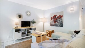 Ein modernes Wohnzimmer mit Flachbildfernseher, einer Lampe, einem Gemälde, einer Couch und einem Couchtisch.