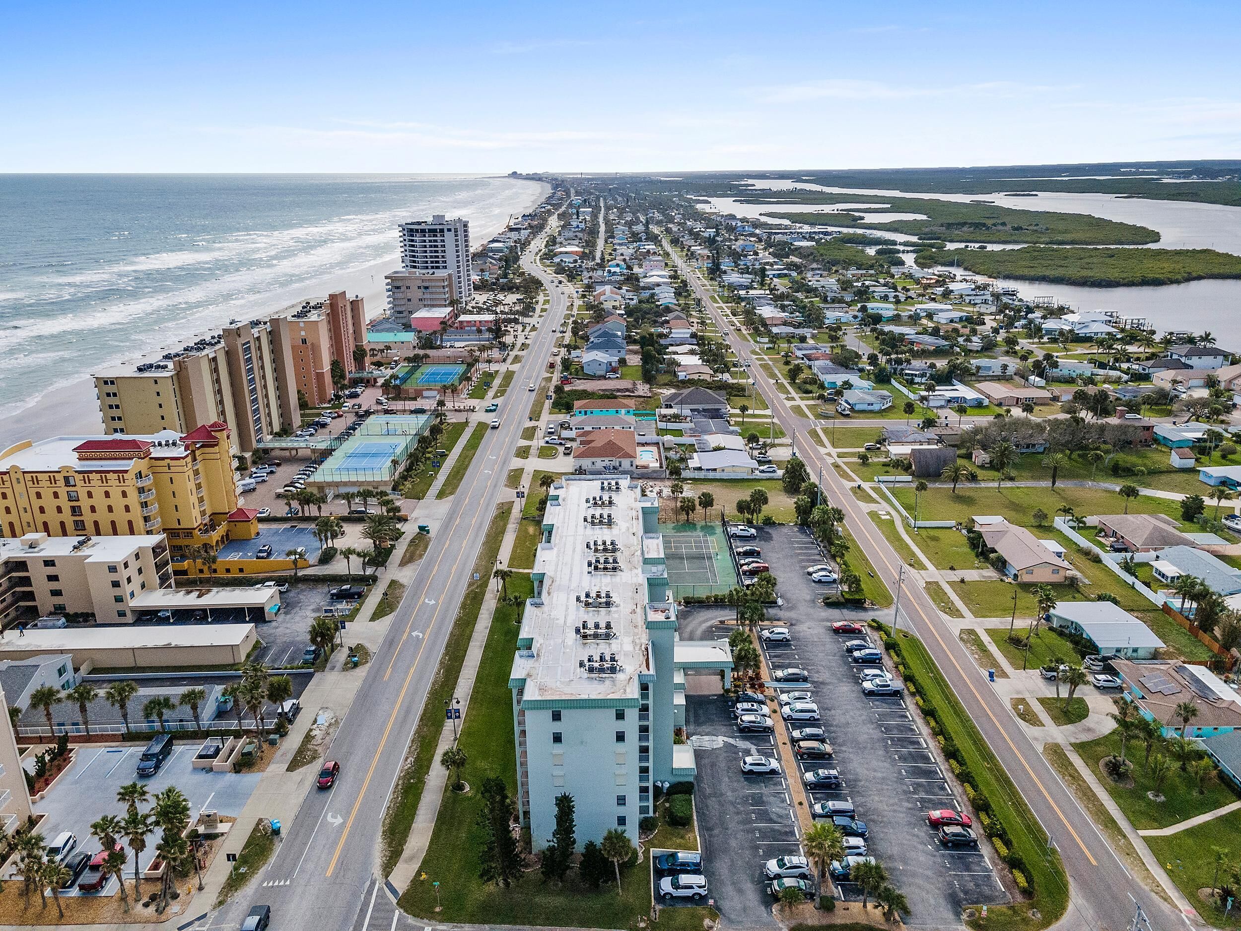 Un paisaje urbano costero con un hotel frente a la playa, calles anchas y zonas residenciales.