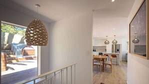 A modern interior with a staircase leading to a dining area and kitchen.