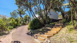 A residential area with a paved road, wooden steps, and lush greenery.