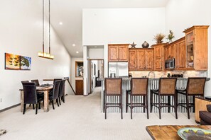 A spacious kitchen with wooden cabinets, a central island with bar stools, and a dining area with a large table and chairs. - Private Hot Tub & Garage, Near Main St/Peak 9 (Breckenridge)