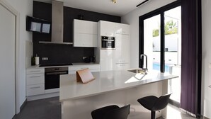A modern kitchen with white cabinets, a black countertop, and a large window. - Villa Levante, Modern Costa Blanca villa with pool and sunny terrace (San Fulgencio)
