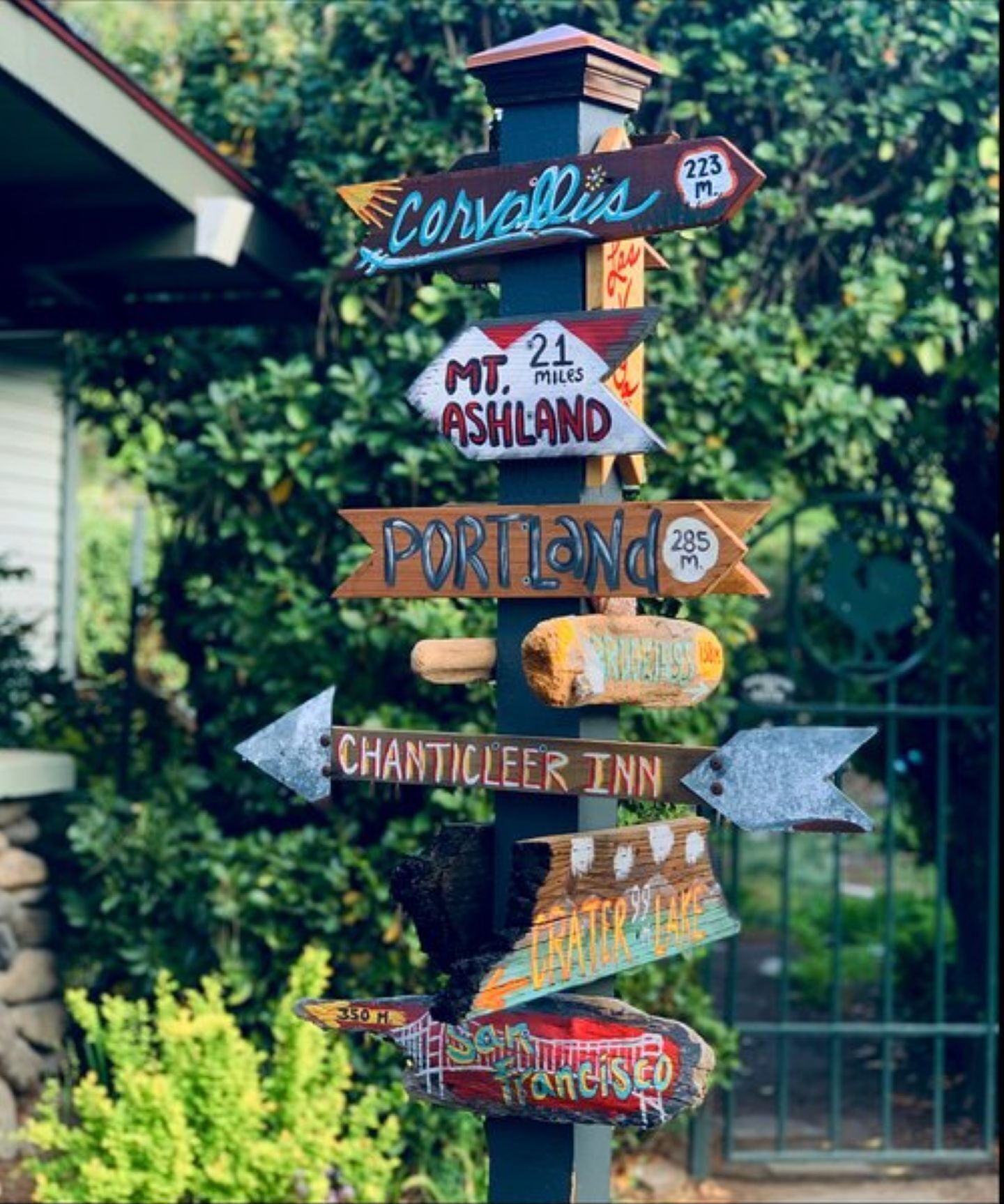 Ein hölzernes Wegweiser mit mehreren Richtungsschildern, darunter Ziele wie Portland und Chanticleer Inn.