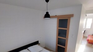 A bedroom with a bed, a nightstand, a wall-mounted lamp, and a sliding door closet. - WEEKLY rental from SATURDAY to SATURDAY facing the sea QUEND PLAGE LES PINS 80 (quend plage les pins)