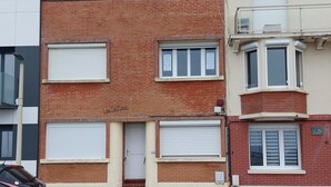 A row of townhouses with closed shutters, a visible door, and a parked car. - WEEKLY rental from SATURDAY to SATURDAY facing the sea QUEND PLAGE LES PINS 80 (quend plage les pins)