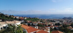 A coastal town with terracotta-roofed buildings, a clear view of the sea, and a hilly backdrop. - Sea View 2 Bedrooms Terrace Villa (Funchal)