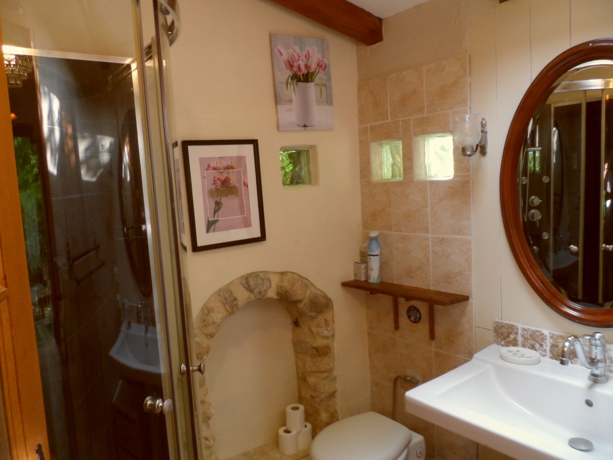 Une salle de bain avec une arche en pierre, des toilettes, un lavabo et un miroir.