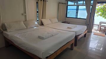 A hotel room with two beds, a window with a view of the sea, and a wooden floor.