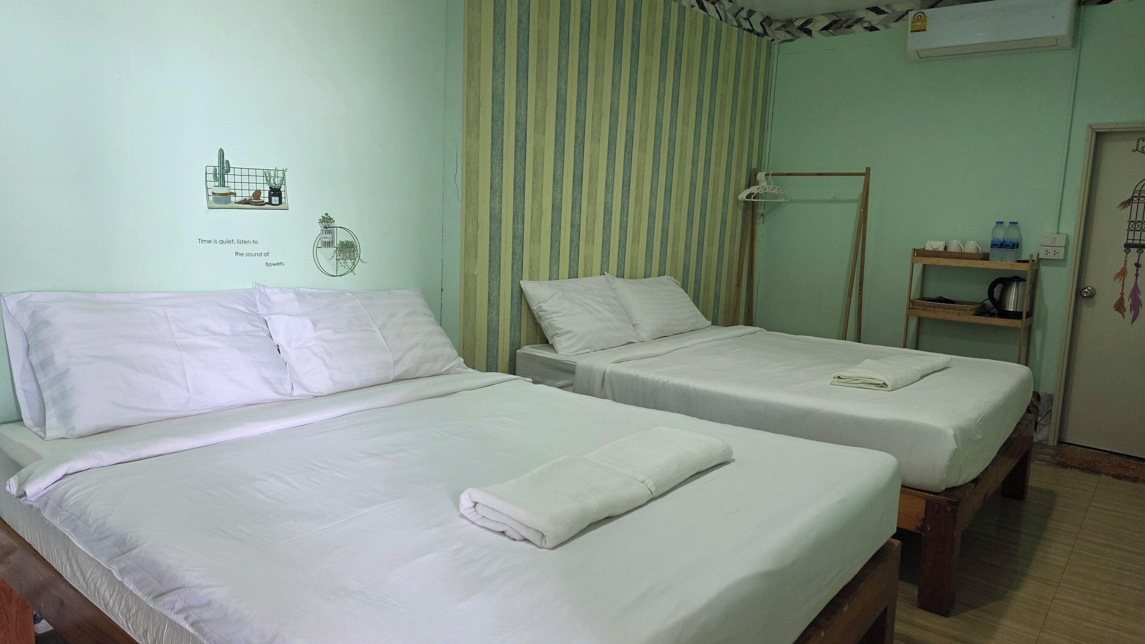 Ein Hotelzimmer mit zwei Einzelbetten, einer kleinen Ablagefläche für Toilettenartikeln und einer Wand mit einem Streifenmuster-Vorhang.