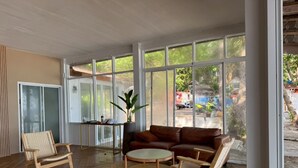 A spacious room with a large window, a brown leather sofa, two wicker chairs, and a small round table. - Samed Big Cape Resort (Rayong)