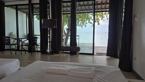A hotel room with a bed, a desk, and a view of the sea. - Samed Big Cape Resort (Rayong)