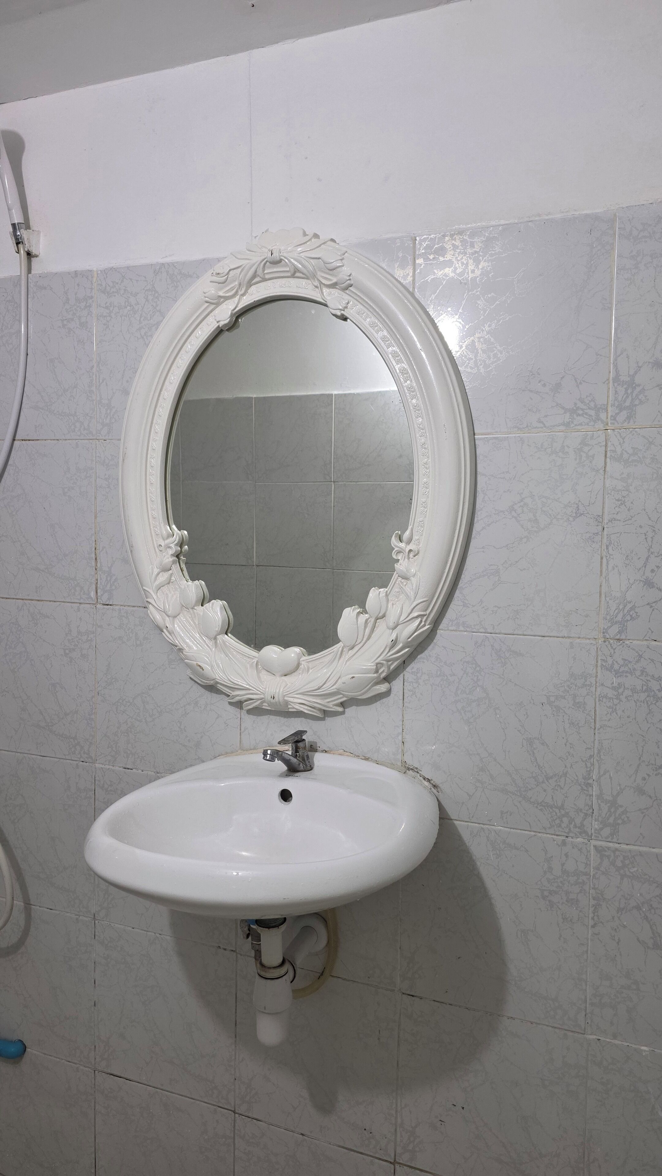 A bathroom with a white marble sink and a decorative mirror with a floral frame.