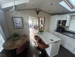 A modern kitchen with white cabinets, a granite countertop, and a built-in microwave.