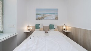 Une chambre à coucher avec un lit, deux tables de chevet avec des lampes, un tableau accroché au mur et une fenêtre avec des rideaux.