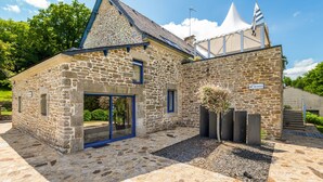 Un bâtiment en pierre avec une porte à cadre bleu, un petit drapeau et une enseigne sur laquelle on peut lire « ARMAEZ ».
