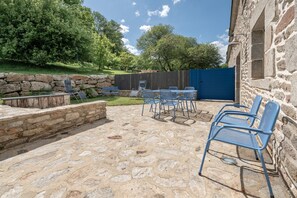 A stone patio with outdoor seating, a stone wall, and a wooden fence.