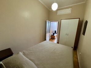 A bedroom with a bed, a wardrobe, and a desk with a chair. - Sea View Madeira Machico 1 Bedrooms Terrace Villa (Machico)
