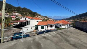 A residential area with houses having red-tiled roofs, a concrete ground, and a clear blue sky. - Sea View Madeira Machico 1 Bedrooms Terrace Villa (Machico)