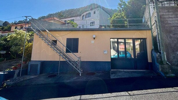 A building with a staircase leading to a door, a small window, and a clear sky. - Sea View Madeira Machico 1 Bedrooms Terrace Villa (Machico)