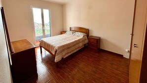 A bedroom with a bed, a desk, and a sliding glass door to a balcony. - Sea View Madeira Machico 2 Bedrooms Terrace Villa (Machico)