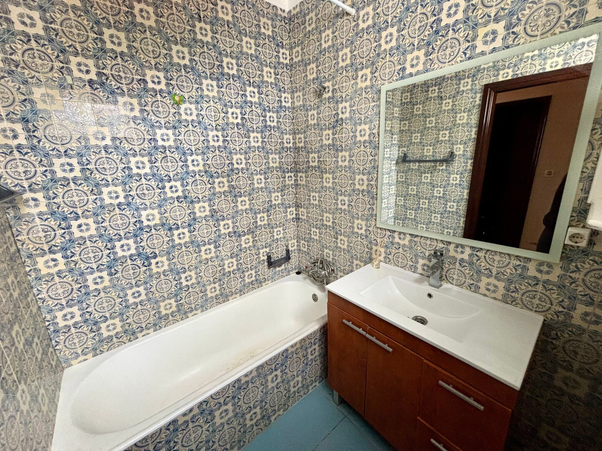 A bathroom with a white bathtub, a wooden cabinet with drawers, and a mirror above the sink.