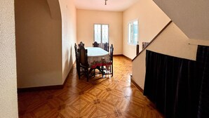 A dining area with a round table and chairs, a wooden floor, and a staircase leading to an upper level. - Sea View Madeira Machico 2 Bedrooms Terrace Villa (Machico)