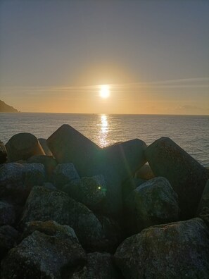 A sunset over the ocean with rocks in the foreground. - Sesimbra 3 Bedrooms With Shared Pool (Sesimbra)