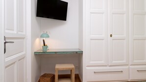 A room with a television mounted on the wall, a small wooden stool, a teal lamp, and a white wardrobe. - Guest Room “A L’abri - An Douar La Terre” with Shared Terrace, Garden, and Wi-Fi (Saint-Nolff)