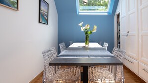 A dining area with a table, chairs, a vase with flowers, a framed picture, and a window. - Guest Room “A L’abri - An Douar La Terre” with Shared Terrace, Garden, and Wi-Fi (Saint-Nolff)