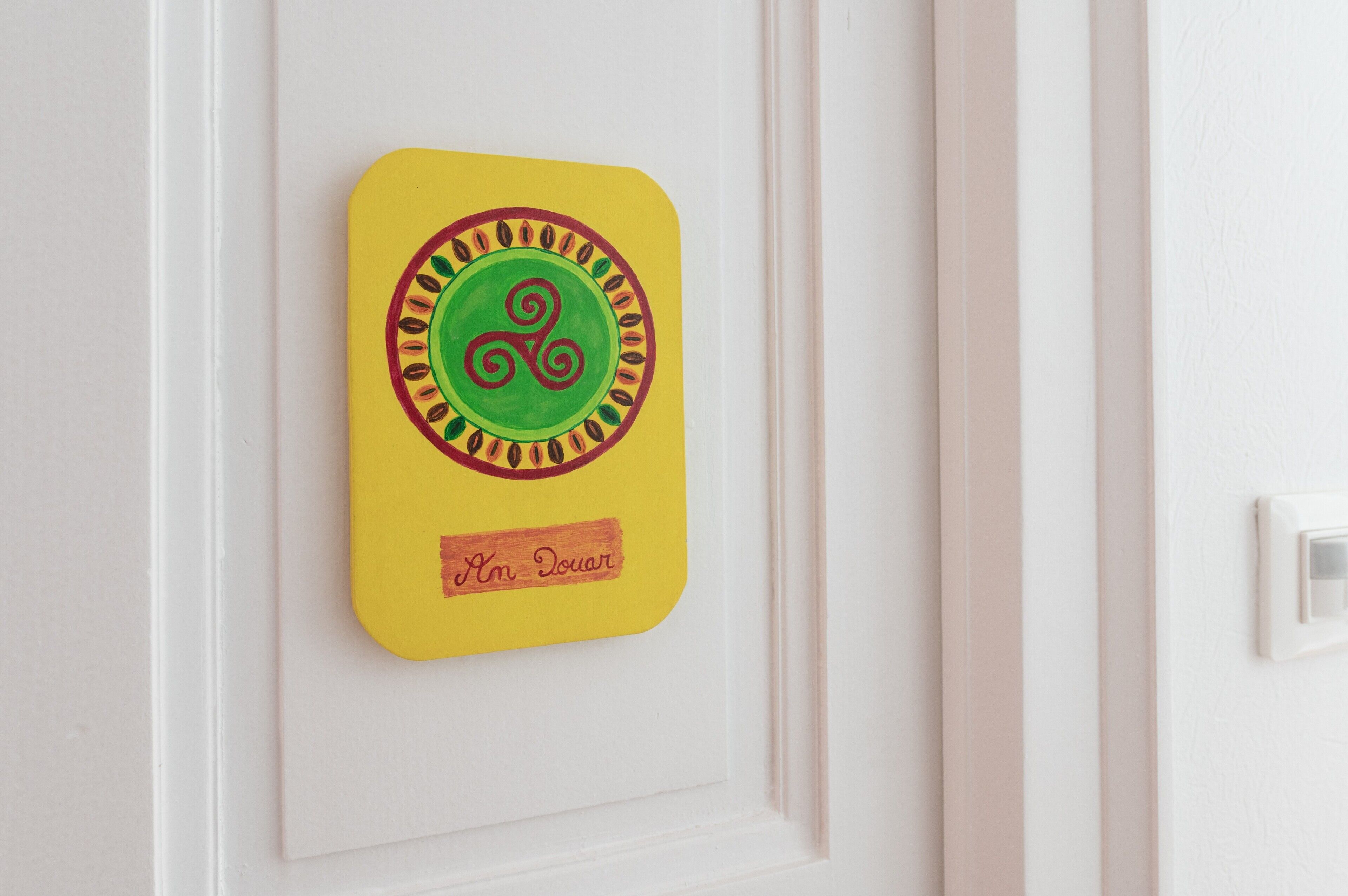 A yellow sign with a green swirl and the text 'Im Douar' on a white door.