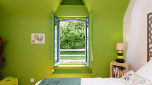 A bedroom with a skylight, a bedside table with books, a lamp, and a bed with a pillow. - Guest Room “A L’abri - An Douar La Terre” with Shared Terrace, Garden, and Wi-Fi (Saint-Nolff)