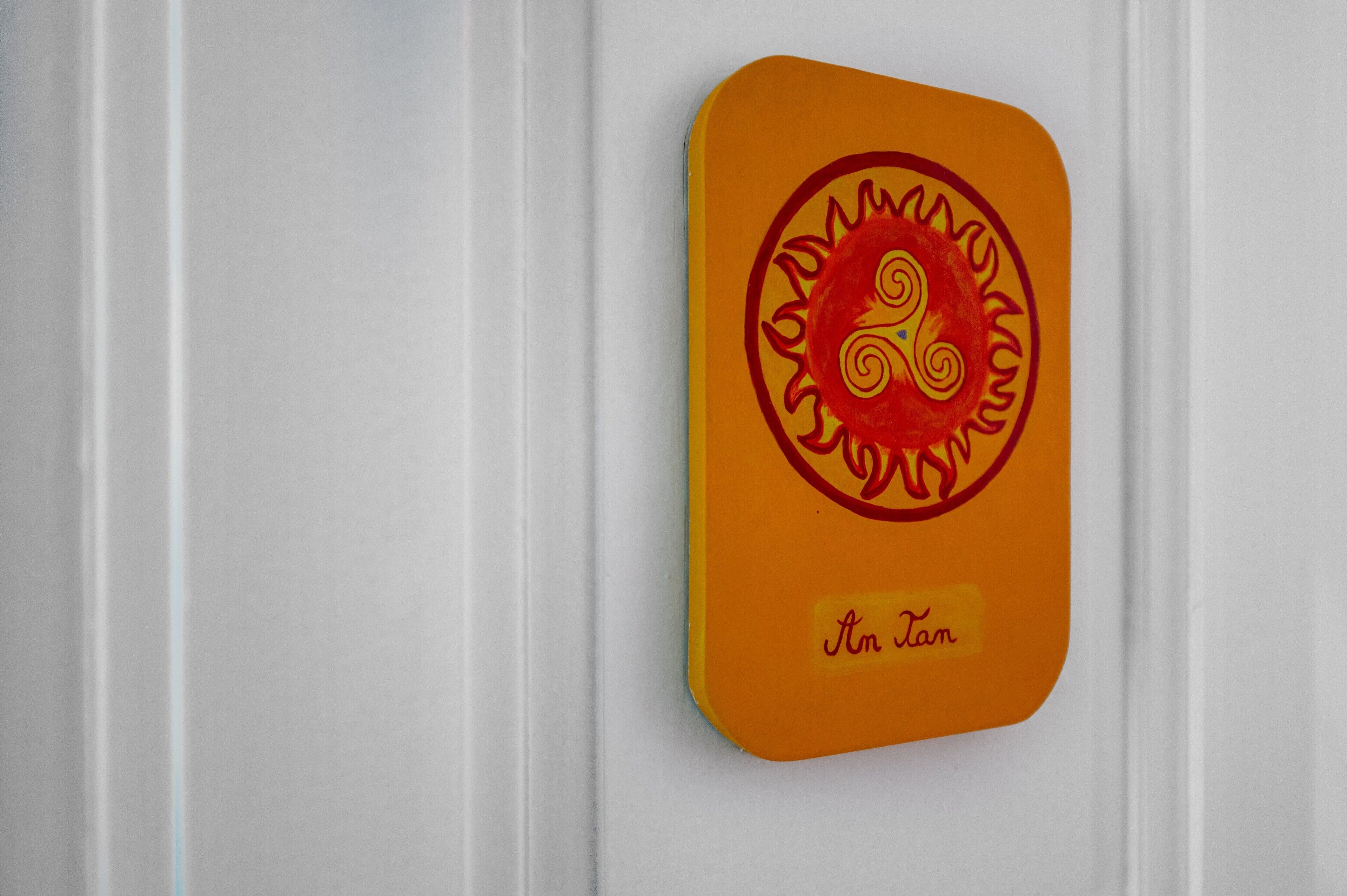 A wall-mounted object with a circular design and the text 'An Tan' on a white background.