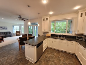A modern kitchen with white cabinets, a granite countertop, and a built-in dishwasher. - Lakefront Winter Rental - Perfect for Snowbirds (Osoyoos)
