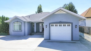 A single-story house with a garage, a front porch, and a driveway. - Lakefront Winter Rental - Perfect for Snowbirds (Osoyoos)