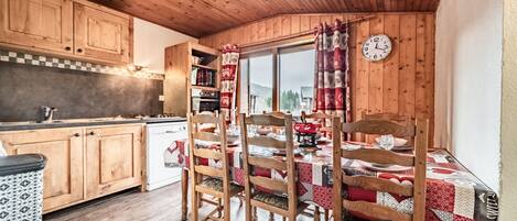 A wooden interior with a kitchen, dining area, and a clock on the wall.