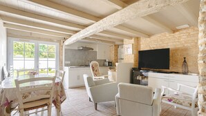 Ein rustikales Interieur mit einem Esstisch, Stühlen, einem Fernseher und einer Küchenzeile.