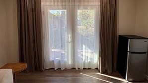 Una habitación con puerta corrediza de vidrio, una pequeña mesa de madera y un refrigerador.