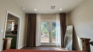 Un dormitorio con cama, ventana, cortinas y vistas al exterior.