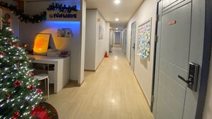 A hotel hallway with a reception desk, a Christmas tree, and lockers.