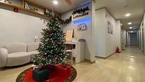 A reception area with a Christmas tree, a sofa, a desk, and a wall-mounted sign.