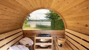 A wooden sauna with a view of a lake, benches, a sauna tub, and a wooden bucket. - Resort Boschmolenplas (Heel)