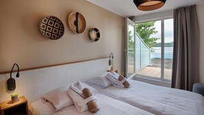 A hotel room with two beds, a large window with a view of the outdoors, and wall decor. - Resort Boschmolenplas (Heel)