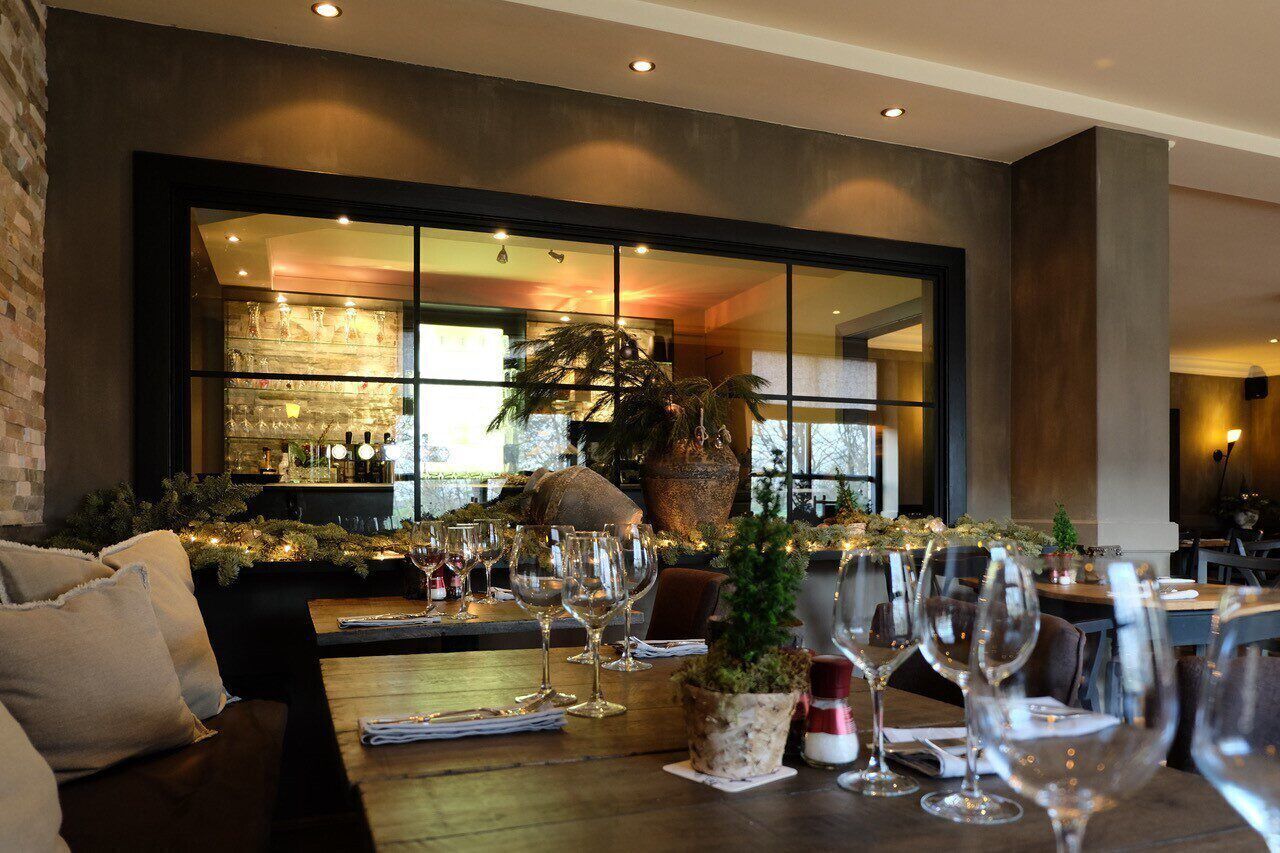 Un interno di ristorante con zona bar, tavoli e sedie in legno.