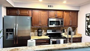 A modern kitchen with stainless steel appliances, wooden cabinets, granite countertops, and a stainless steel sink. - Spacious  2BD Condo  HWY360/30  Grand Prairie (GP22B) (Grand Prairie)