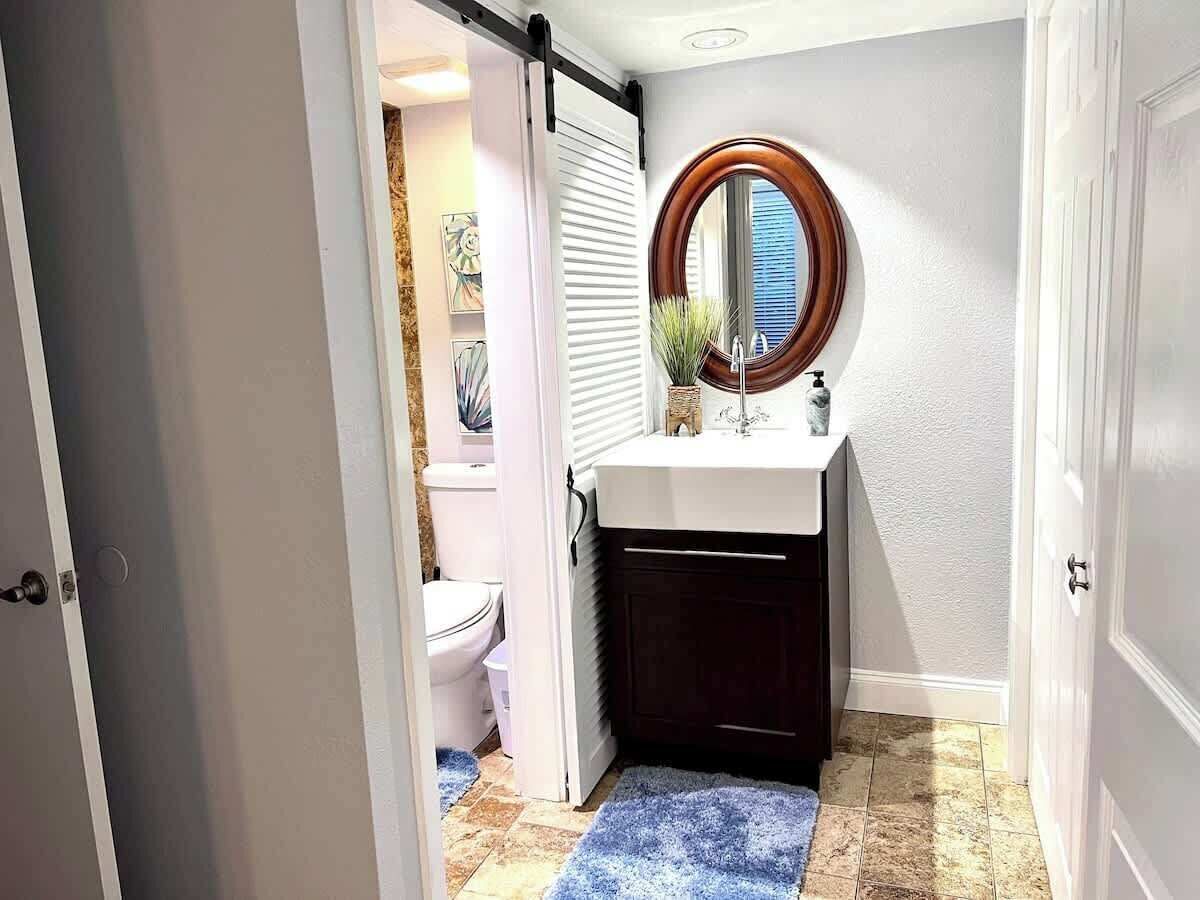 Un bany amb un lavabo blanc, un mirall rodó i un vàter.