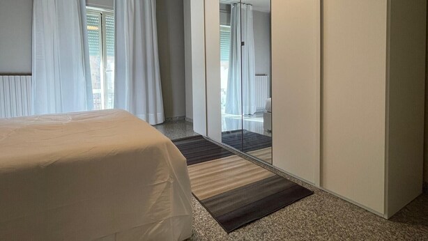 Ein Hotelzimmer mit Bett, einem großen Spiegel und Blick nach draußen.